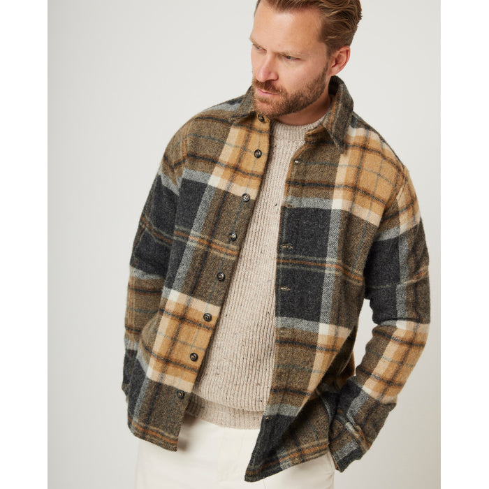 Flatlay image of a checked wool collared shirt with eight black buttons fastening down the front center of the shirt, it is a checked pattern consisting of a dark grey and sand as the main base colours and a white thin strip running through the squares.