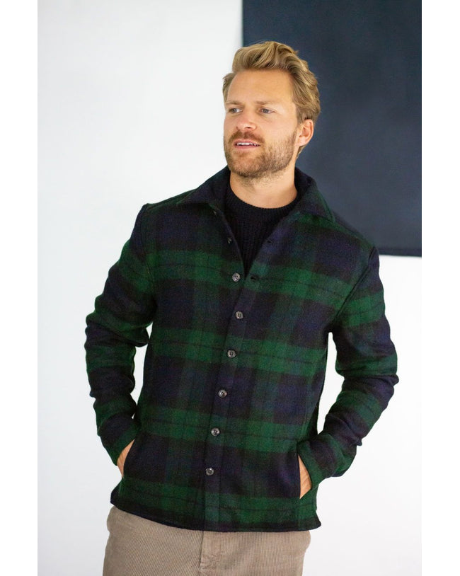 Flatlay image of a checked wool collared shirt with eight black buttons fastening down the front center of the shirt, it is a checked pattern consisting of navy and a dark forest green.