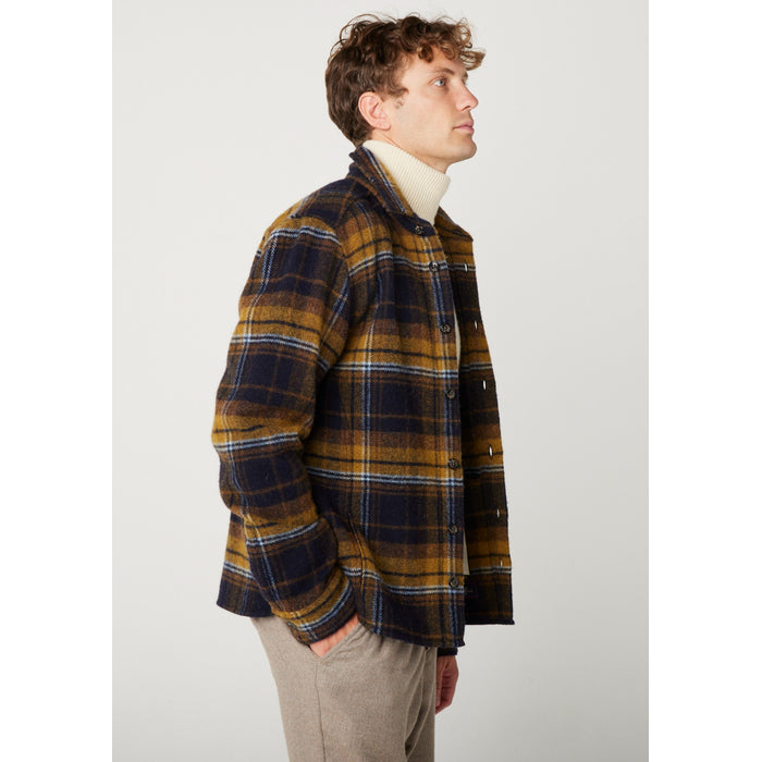Flatlay image of a checked wool collared shirt with seven black buttons fastening down the front center of the shirt, it is a checked pattern consisting of navy, mustard and white rim around the squares.