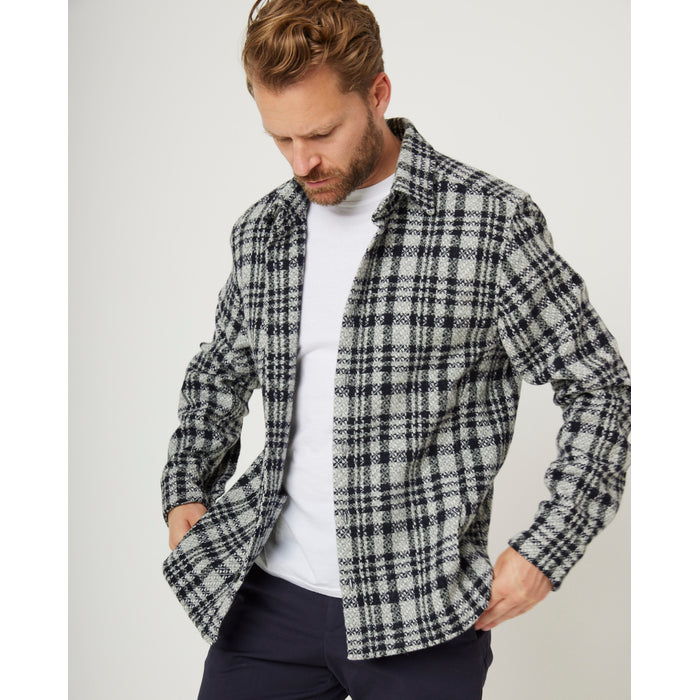 Flatlay image of light grey and black checked wool shirt with seven buttons down the center front fastening the collared shirt closed, the shirt has a slightly curved hem.