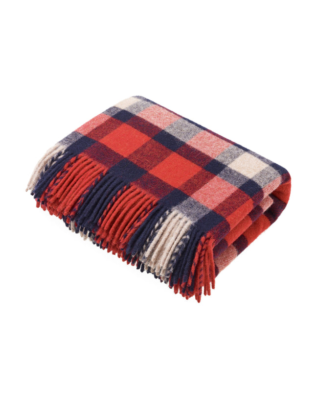 Flatlay image of a wool blanket folded into a small rectangle, the edge of the blanket is fringed, the blanket is multi-coloured check with alternating shades of dark red, faded red, navy, faded navy and cream. Image of the blanket laid out flat with fringing on both edges.